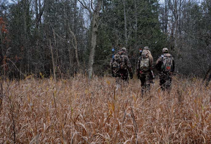 Three hunters walking through field